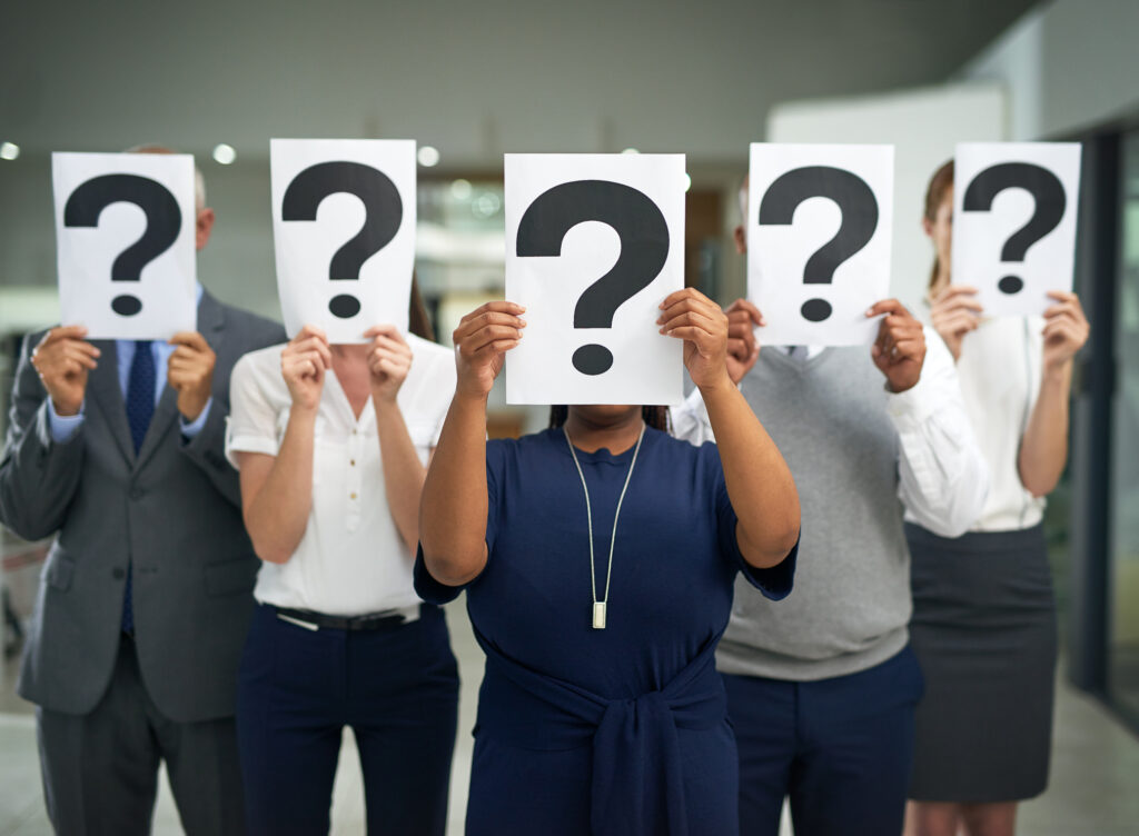 Shot of a group of businesspeople holding questions marks in front of their faces