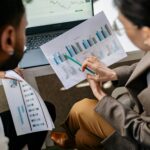 Colleagues collaborating on data charts and discussing business strategies in an office setting.