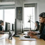 A team of call center agents working in a modern office with headsets and computers.