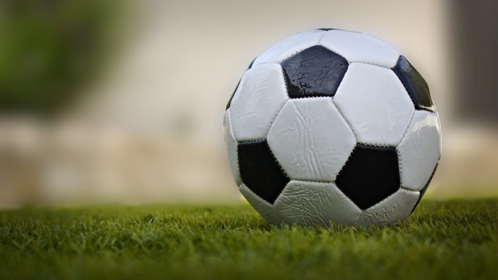 A classic soccer ball rests on green grass.