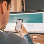 man in black suit holding white iphone 5